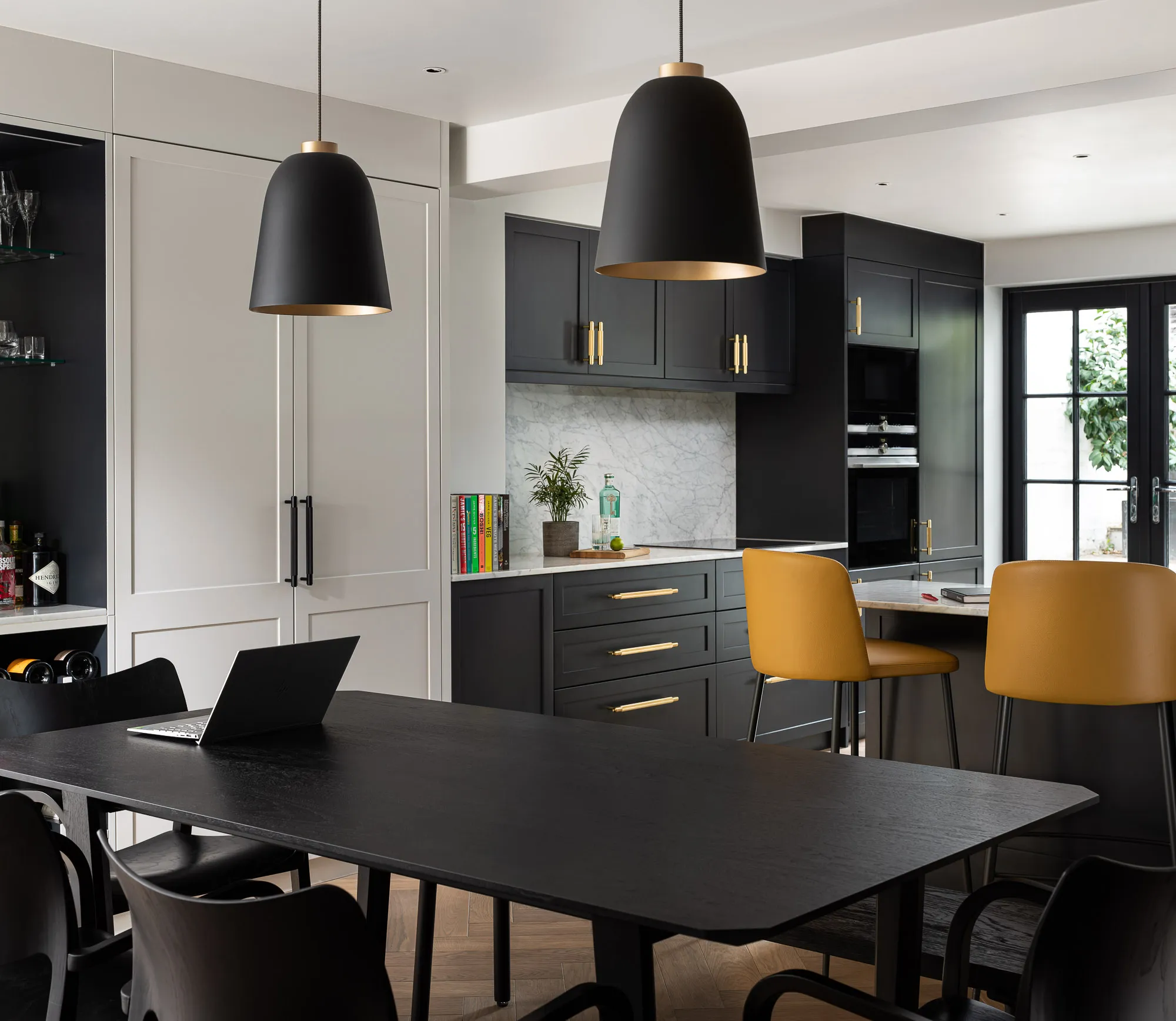 Black kitchen cabinetry with brass handles and pendants