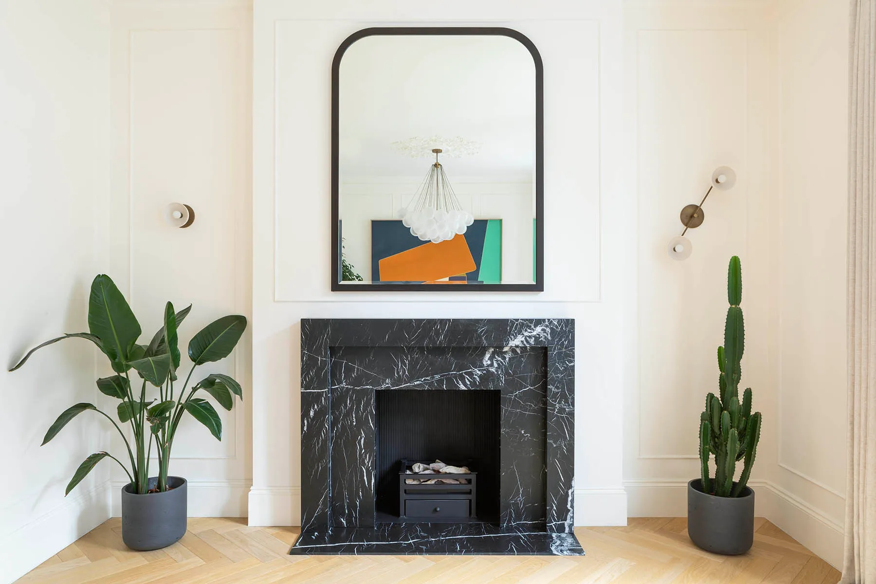 Black marble fireplace below an arched mirror