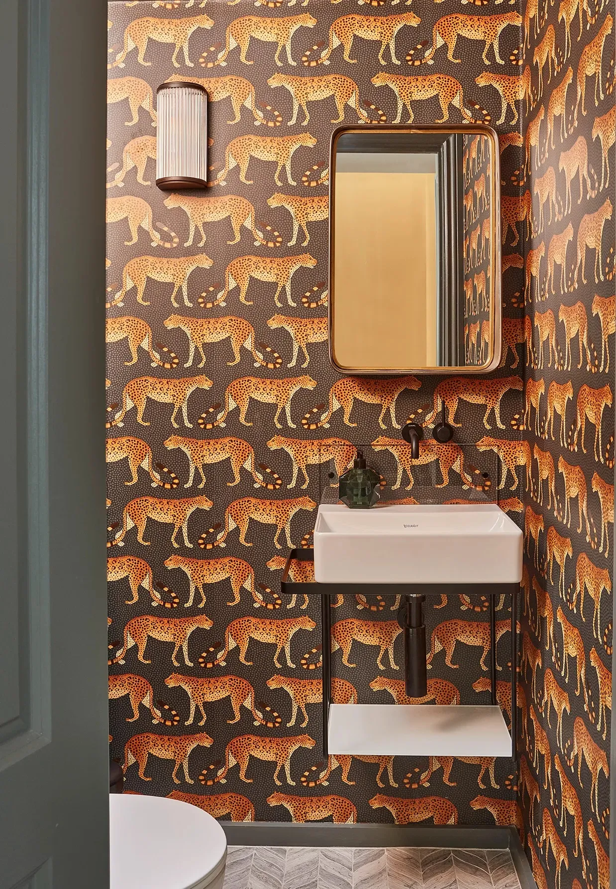 Cloakroom basin against leopard-print wallpaper