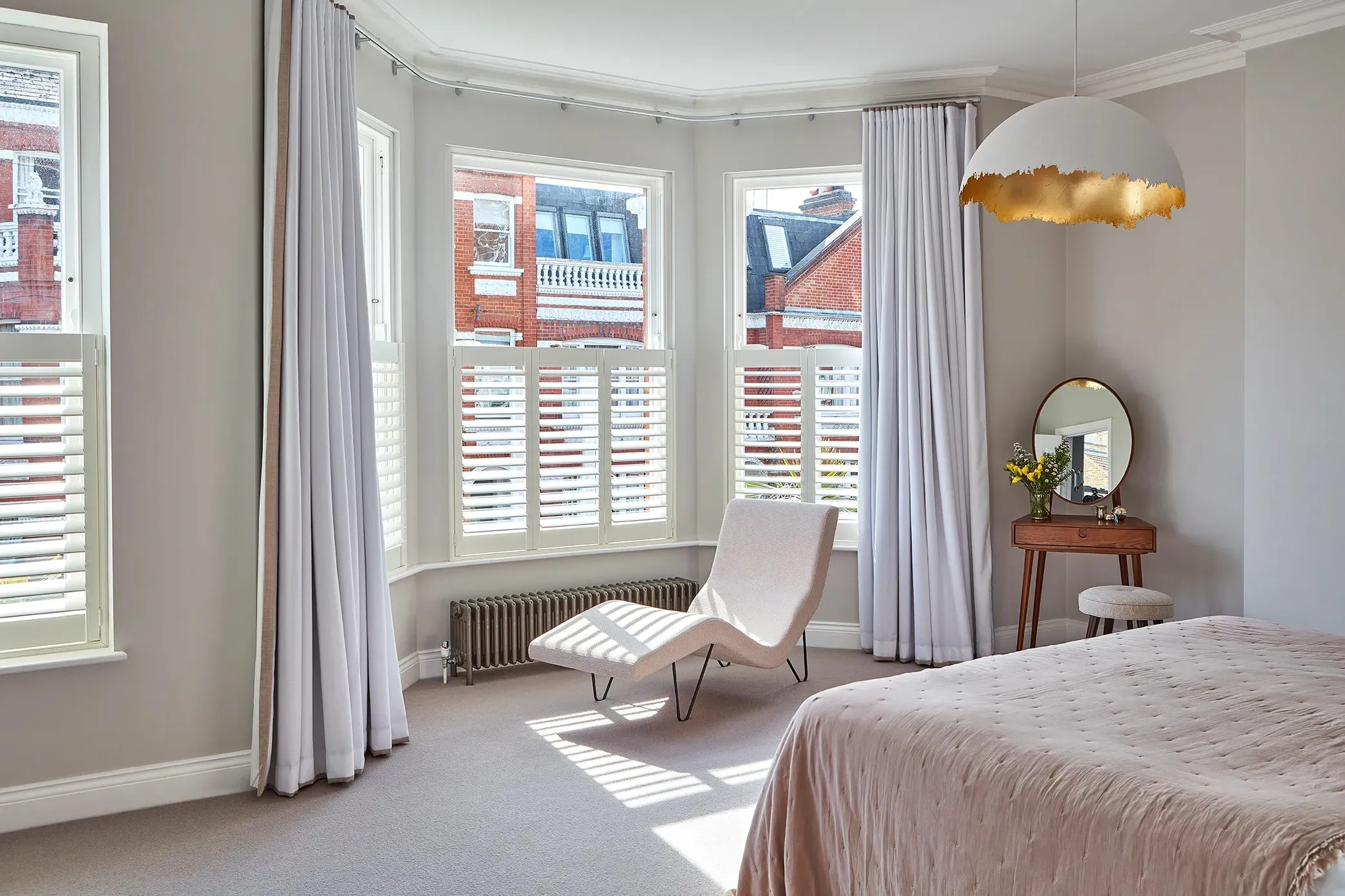 Bedroom bay window with shutters and long curtains