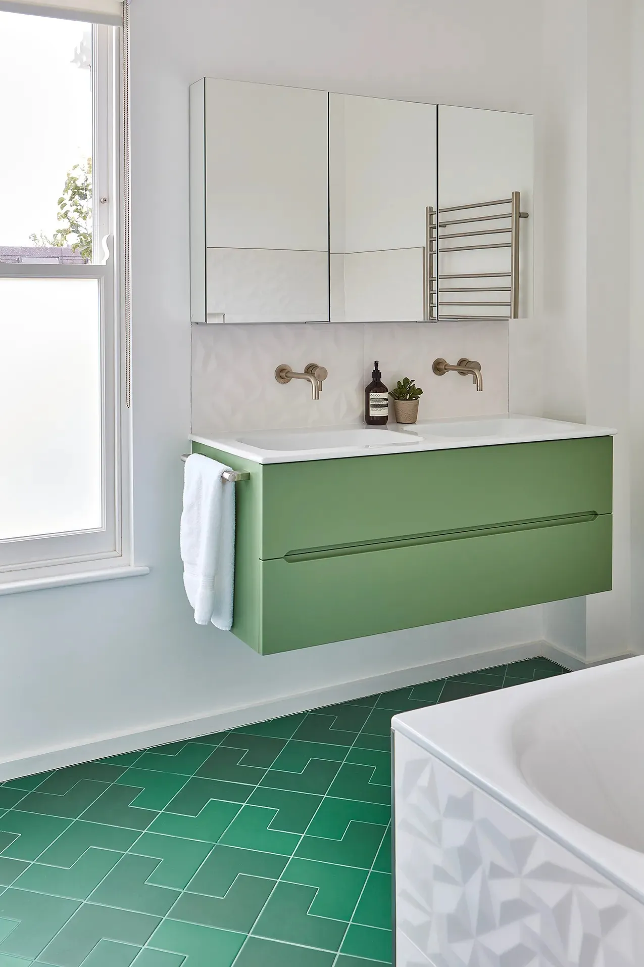 Green vanity unit and bath in a bathroom