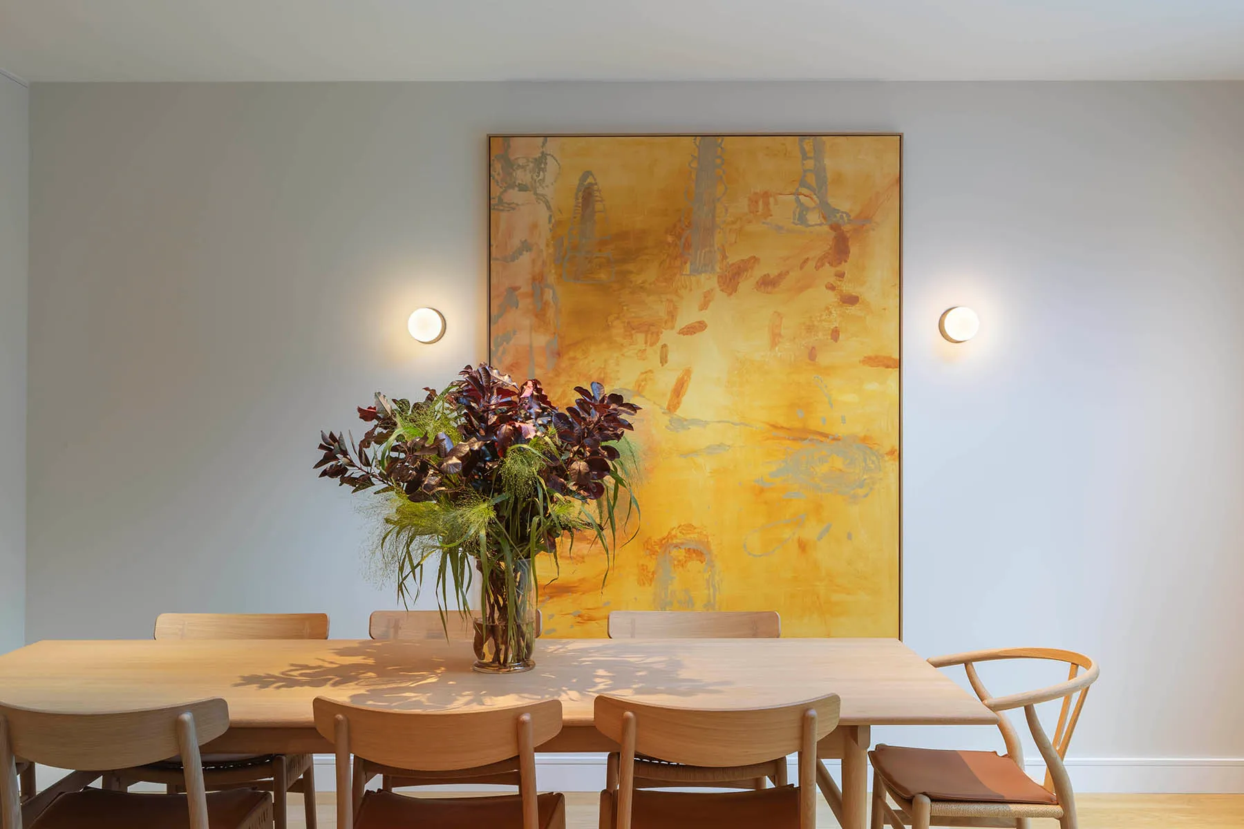 Dining table below a gold canvas